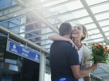 Germany, Leipzig-Halle, Airport, Couple embracing, Man holding flowers