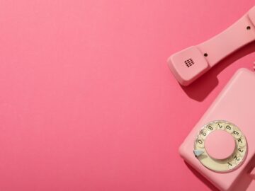 Landline phone on pink background, space for text
