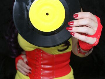 Woman in 1980s yellow clothing holding 45rpm record. Record label painted with yellow poster paint
