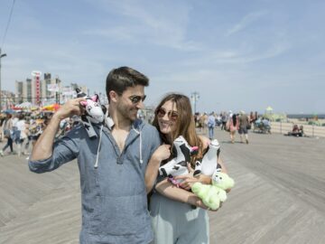 Couple holding cuddly toy cows smiling, Coney island, Brooklyn, New York, USA