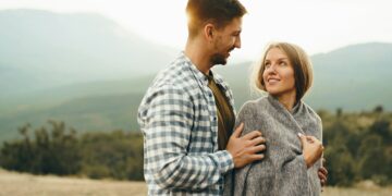 Happy loving couple hiking and hugging in mountains