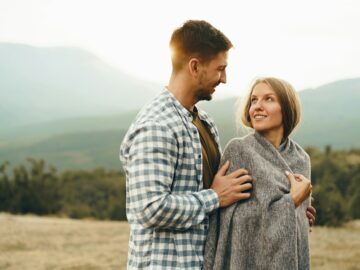 Happy loving couple hiking and hugging in mountains