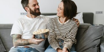 Happy young white couple watching TV