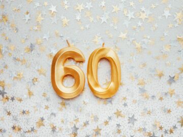 Number 60 sixty golden celebration birthday candle on Festive Background.